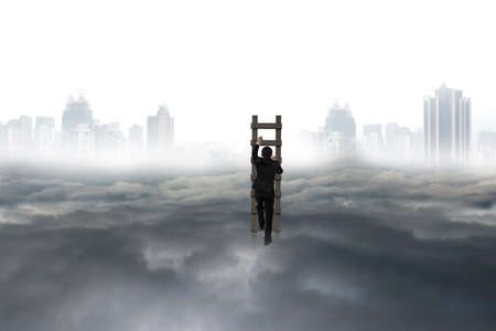 Business man climbing on wooden ladder with city landscape gray cloudscape backgroundの写真素材