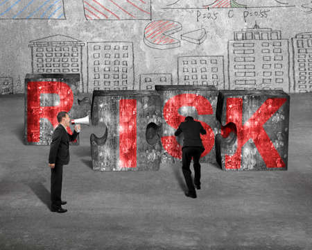 Boss using speaker yelling at employee pushing big jigsaw puzzle concrete blocks with red RISK word, on business doodles wall backgroundの写真素材