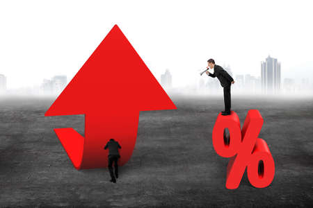 Manager using speaker yelling at businessman pushing red trend 3D arrow upward, with red percentage sign on gray concrete floor backgroundの写真素材