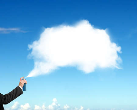 Male hand spraying white cloud paint on blue sky backgroundの写真素材