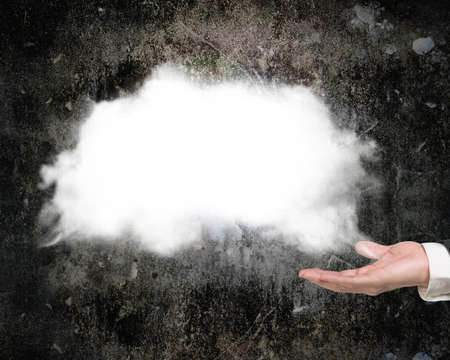 Male hand showing white cloud with dark concrete wall background
