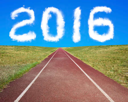 2016 year shape clouds in the blue sky, with dark red running track and grass.の写真素材