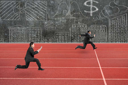 Two businessmen running on red track, with business concepts doodles wall background.の写真素材