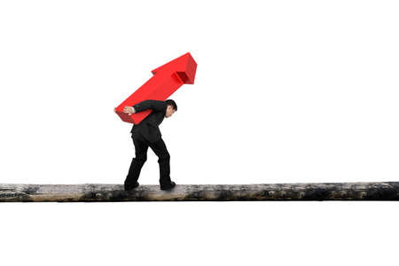Businessman carrying red arrow sign balancing on tree trunk, with white background.
