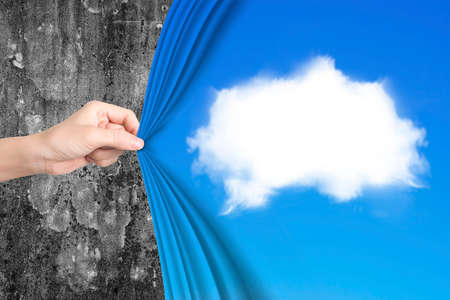 Woman hand pulling open white cloud blue curtain covering old mottled concrete wall.の写真素材