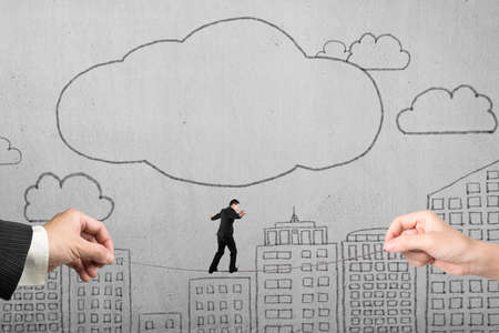 Businessman balancing on tightrope with man and woman hands holding two sides, on doodles concrete wall background.の写真素材
