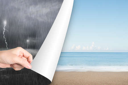 Woman hand open calm sea beach page to replace dark stormy oceanの写真素材