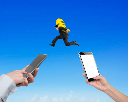Human hands using different smart phones to transfer money, with businessman carrying euro sign jumping, electronic trading concept.の写真素材