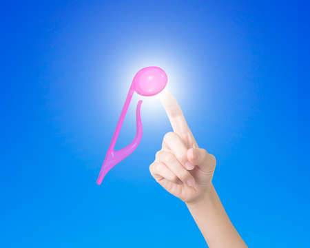 Female finger touching 3D music note with bright light, front view, on blue background.の写真素材