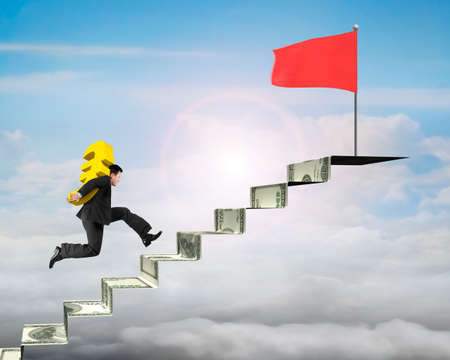 Businessman carrying gold Euro running to red flag on money stairs with sky backgroundの写真素材