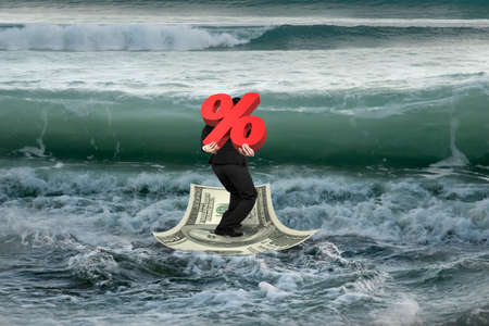 Businessman carrying 3D symbol of percentage on money boat in sea with wave comingの写真素材
