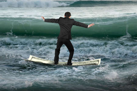 Businessman standing and balancing on money boat floating in the ocean with oncoming waves