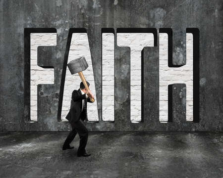 Faith word on concrete wall with man holding hammer, on concrete floor indoors background.の写真素材