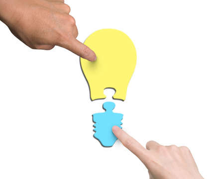Woman and man two hands assembling one bulb shape puzzle of two jigsaw pieces with different color yellow and blue, high angle view, isolated on white.の写真素材