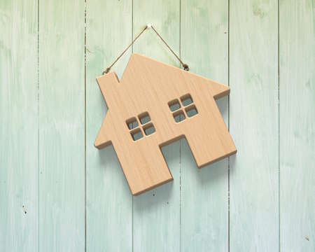 Wooden house hanging on green wood wall background.の写真素材