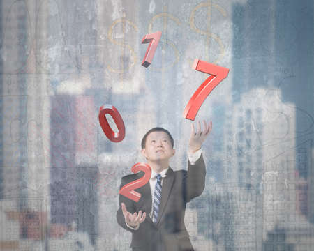 Man catching throwing 2017 red words, on city buildings background.