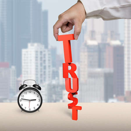 Hand stacking TRUST on table, in office
