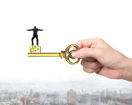 Rear view of man balance on treasure key in pound sign shape with hand holding, on urban scene background.の写真素材