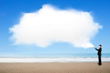 Man spraying white cloud paint standing on sea beach background.の写真素材