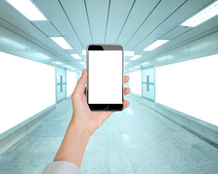 Woman hand holding smart phone with blank white screen in underpass background, front view.の写真素材