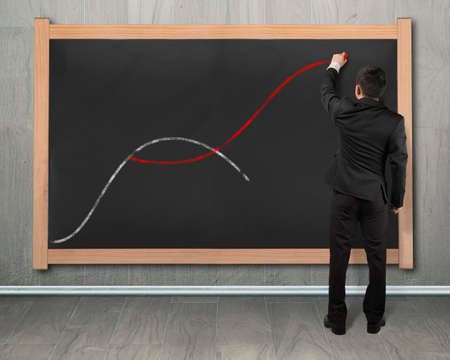 The second curve concepts, man holding chalk drawing two curves on black chalkboard.の写真素材