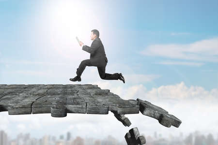 Man using tablet and running on concrete puzzle ground with some pieces falling.の写真素材