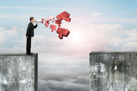 Man using megaphone yelling with 3D thumbs down spraying out, on top of high concrete wall.の写真素材