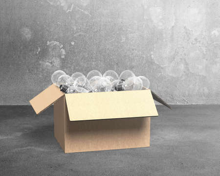 Open cardboard box with light bulbs, on concrete wall and floor indoors background.の写真素材