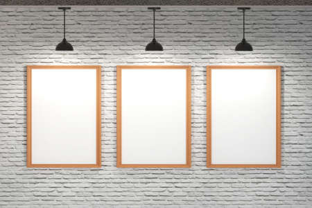 Three blank white frame poster on brick wall with ceiling lamps and white light.の写真素材