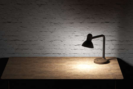 Table lamp with yellow light illuminated the wooden tabletop and whtie bricks wall.