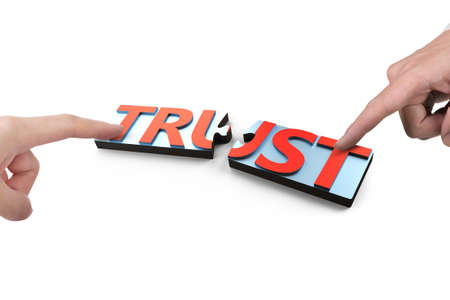 Two forefingers pointing and pushing puzzle pieces with red word TRUST together, isolated on white...