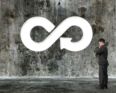 Circular economy concept. Thinking businessman in front of white arrow infinity recycling symbol...