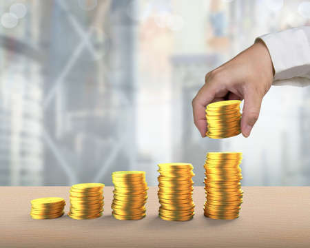 Man's hand arranging golden coins to stack as step stairs on the table, concept of financial growth...