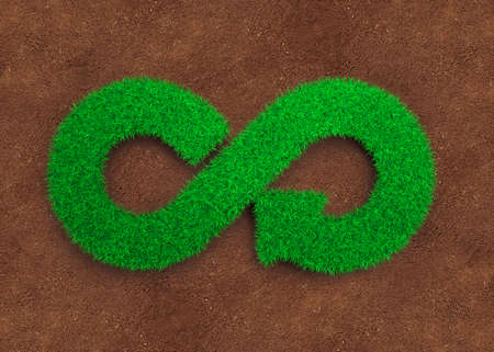 ECO and circular economy concept. The green grass in form of arrow infinity recycling symbol and red soil background.の写真素材