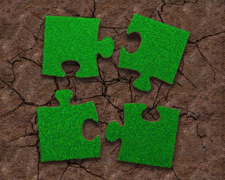 Four jigsaw puzzles of green grass texture, on dry red soil background, high angle view.の写真素材