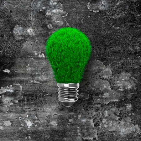 Light bulb with green grass on dark dirty concrete wall background, ECO green energy concept.