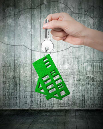 Buying green property concept - Hand holding silver key with green house key ring.の写真素材