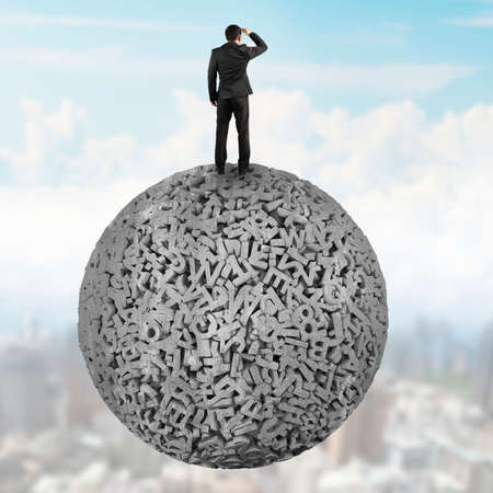 Big data concept. Rear view of businessman standing on gray concrete ball of huge amount 3d letters and numbers, on cloudy sky cityscape background.の写真素材