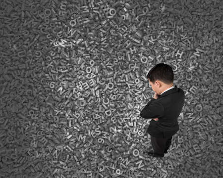 Big data concept, Thinking business man standing and looking at huge amount of 3d dark grey concrete...