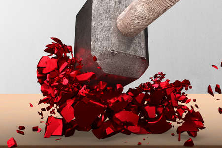 Sledgehammer smashing red percentage sign cracked on wooden table with concrete wall background.の写真素材