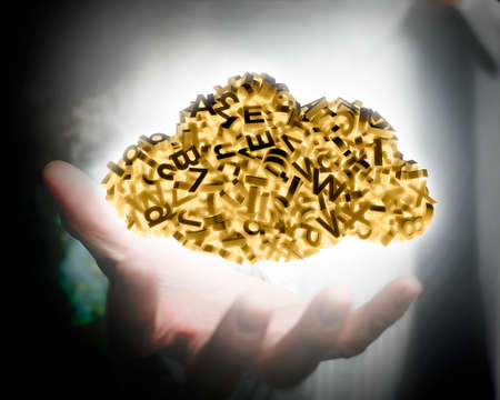 Big data and cloud computing concept. Business man hand holding yellow cloud of 3d letters and numbers, self-illuminated.の写真素材