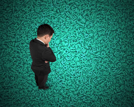 Big data concept, Thinking business man standing and looking at huge amount of 3d green concrete letters and numbers texture background.の写真素材