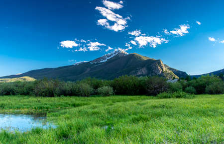 Mountain peak with snow, with grassy meadow as foregrouind. Recreation,travel,inpirational concepts.の写真素材