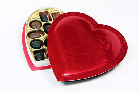 Heart shaped box of chocolates with the lid partially off to show the candy inside.の写真素材