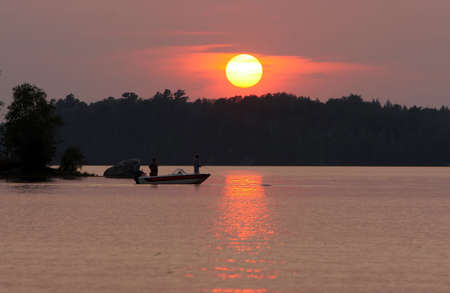 Two men fishing on a remote Wisconsin lake at sunset.の写真素材