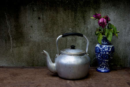 Old silver kettle and vase flower rose  placed on a wooden floorの写真素材