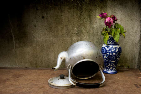 Old silver kettle and vase flower rose  placed on a wooden floor
