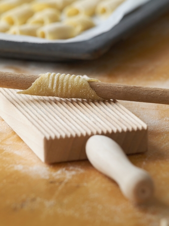 Italian home made fresh pasta Garganelli wrapped around on handle of wooden spoon.の写真素材