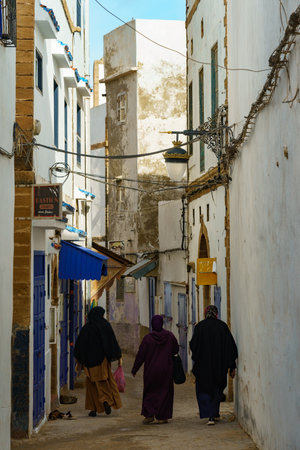 Morocco. Essaouira. Three women dressed in djellaba walk down a street in the medinaのeditorial素材