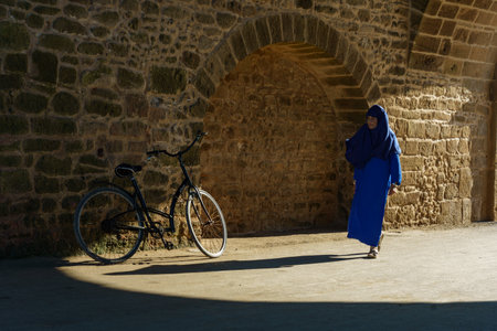 Morocco. Essaouira. A woman wearing djellaba walking in a street of the medinaのeditorial素材
